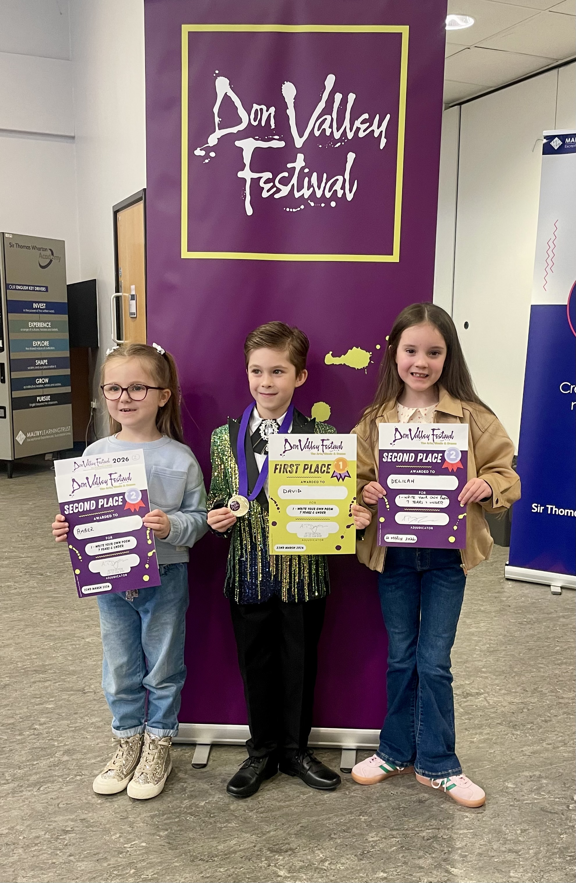 Three young poetry entrants celebrating with their certificates at the 2026 Festival.